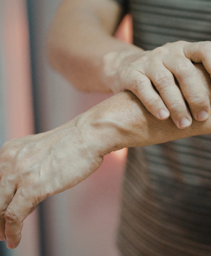 Close-up of a person holding their forearm because of muscle weakness and discomfort